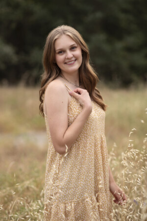 Brunette teen girl standing in a field of wheat colored weeds.